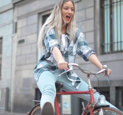 Smiling woman riding a vintage bicycle in a lively city street.