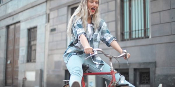 Smiling woman riding a vintage bicycle in a lively city street.